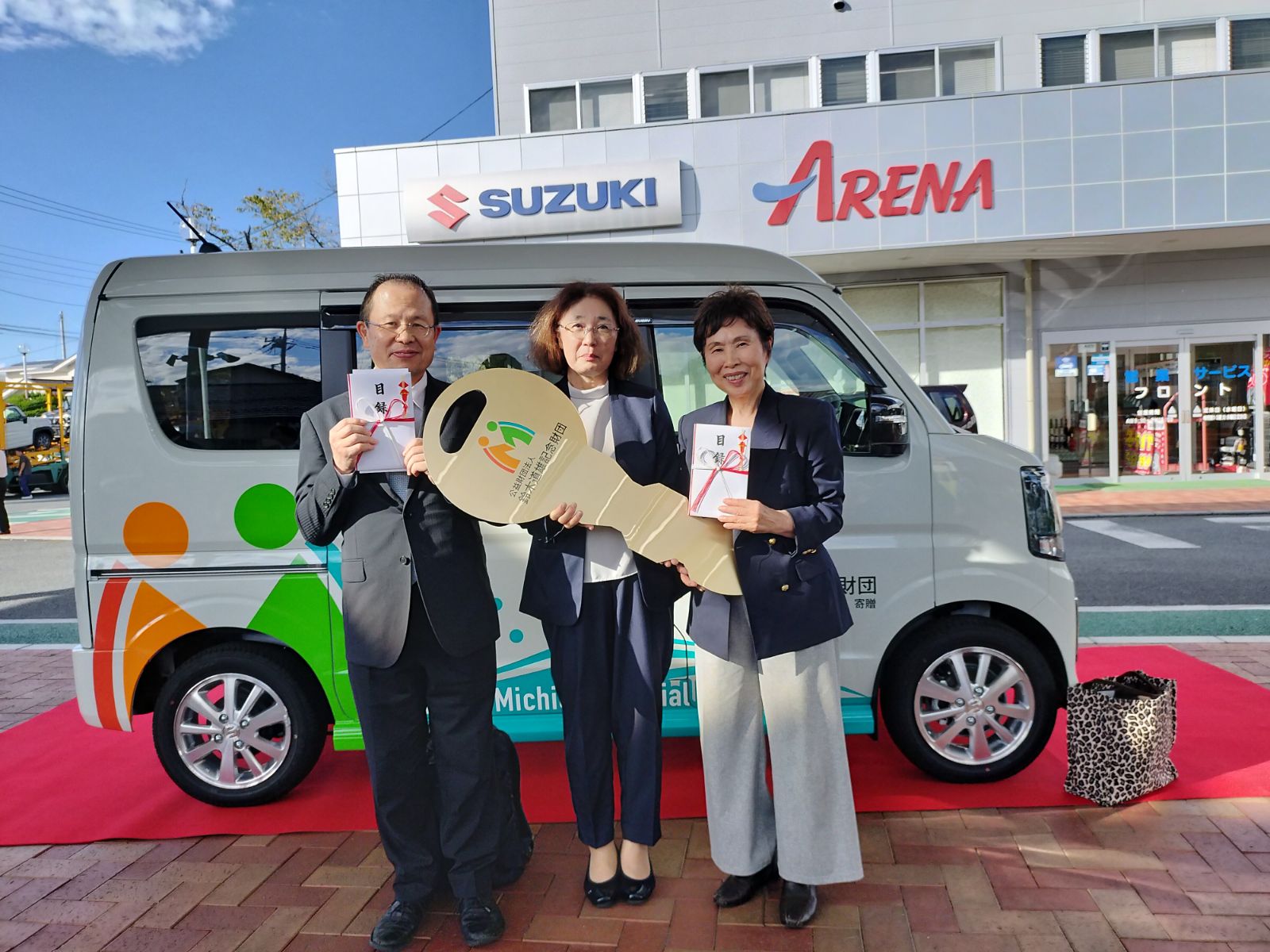 福祉車両の贈呈式で、寄贈車両の前に目録と大きな鍵を持って並ぶ関係者の皆さま
